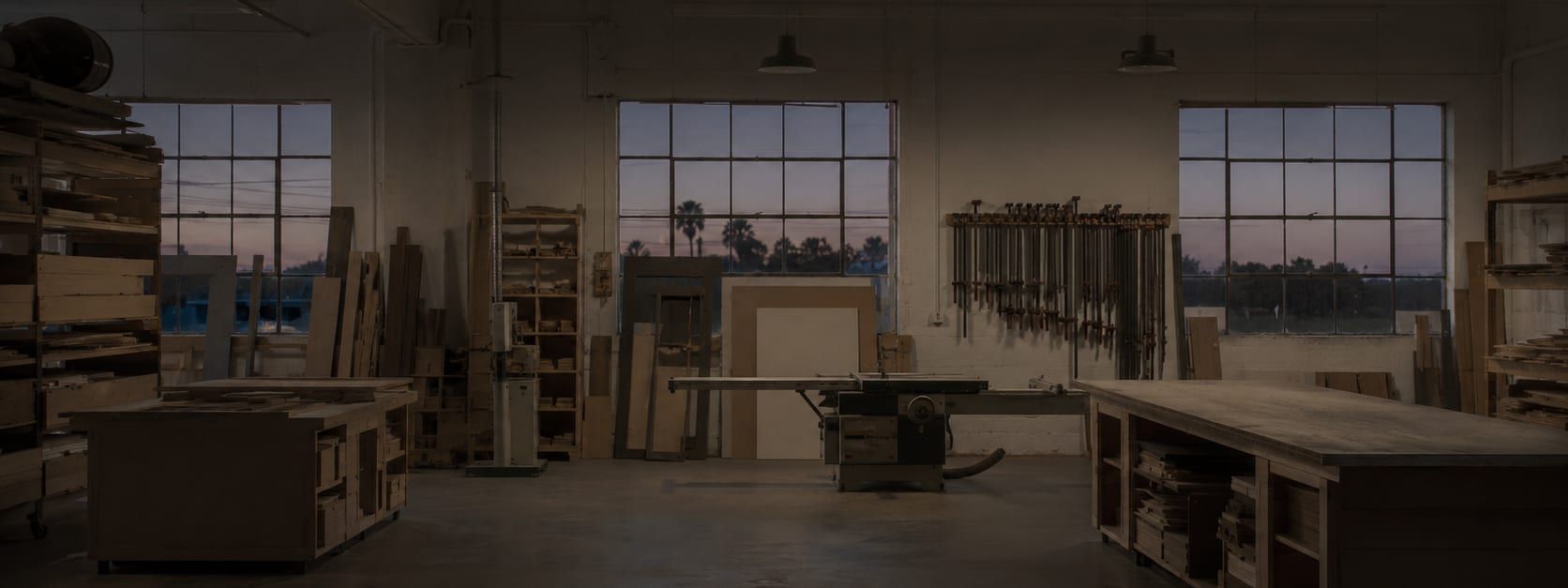 A cabinet shop bench with clamps, a finished door and shop drawings laid out