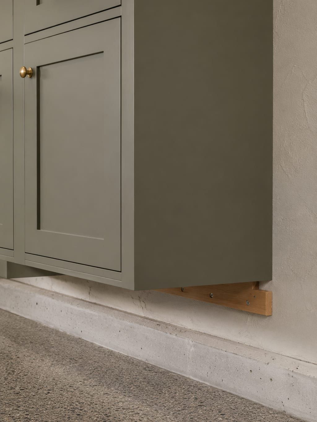 The underside of a wall hung garage cabinet showing clear space above the concrete floor
