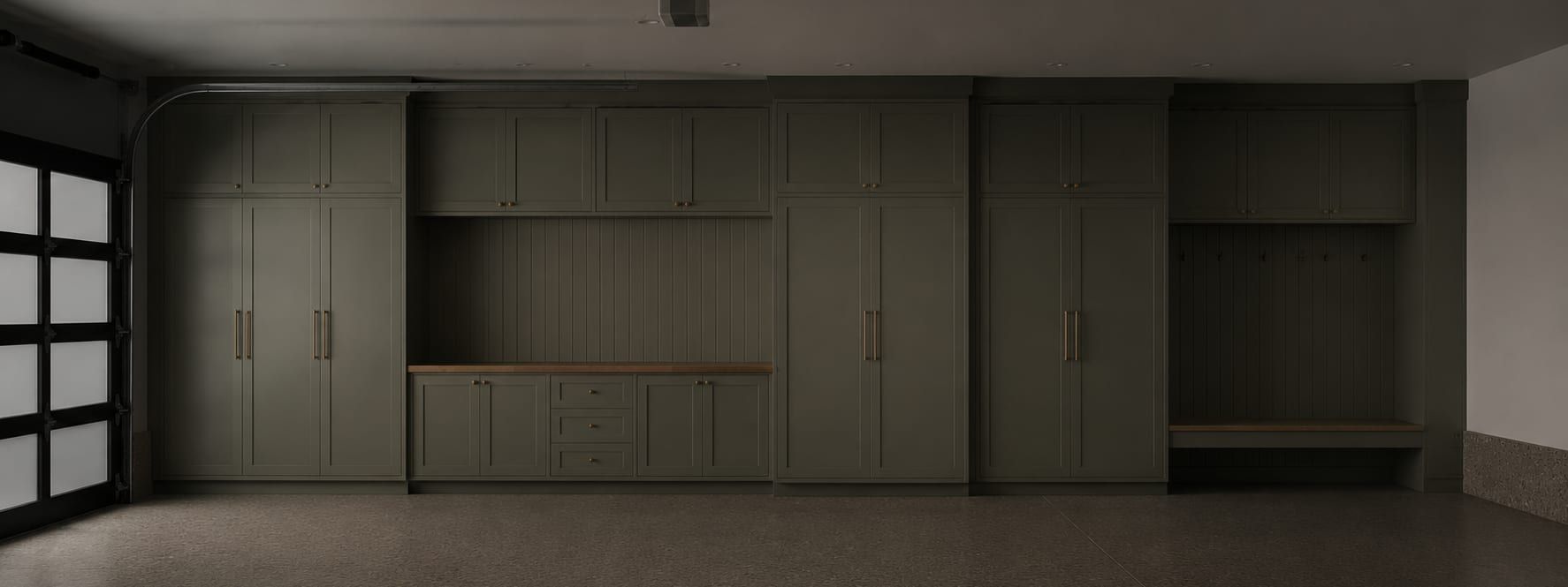 An open garage door seen from the driveway with a finished storage wall inside