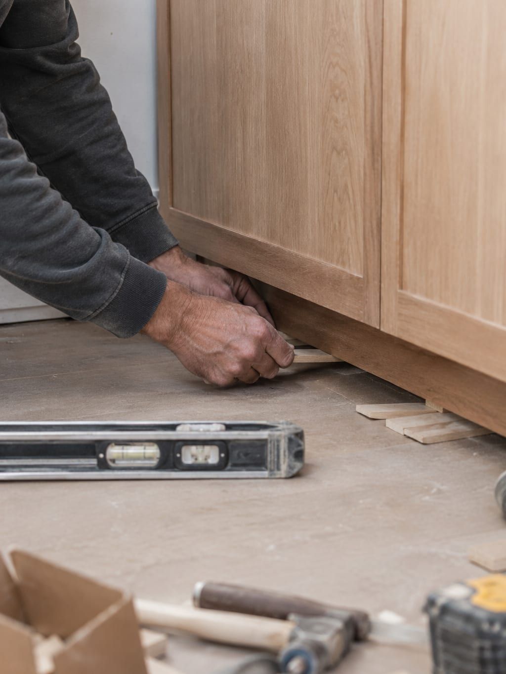 Shims stacked under the corner of a base cabinet to bring it up to a level line