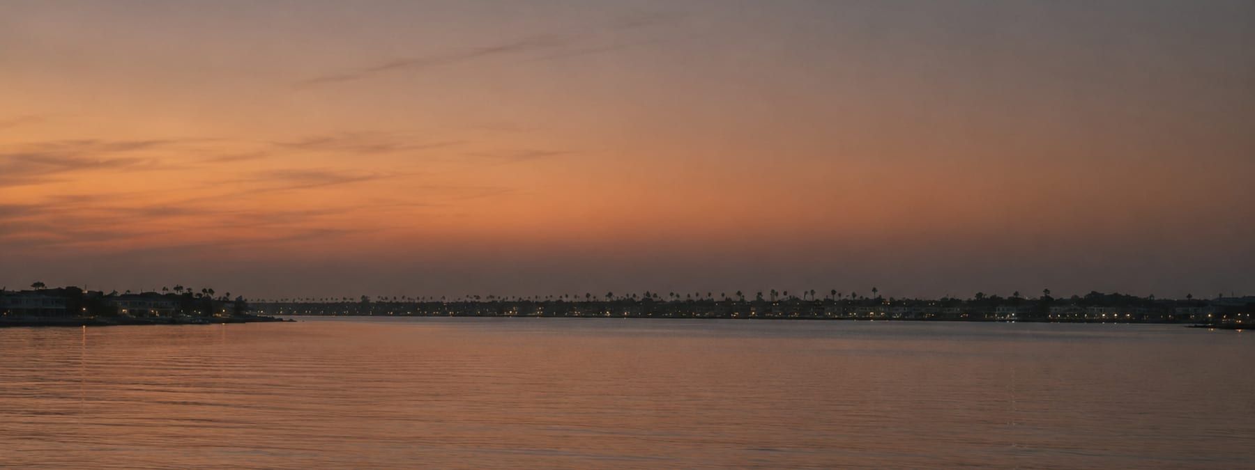 A Newport Beach street of waterfront homes seen from across the channel