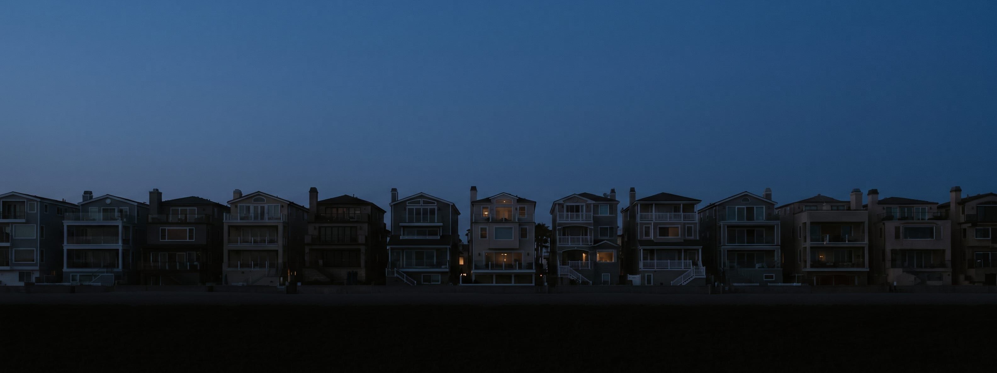 Tall narrow beach houses lining the Sunset Beach strip seen along the street
